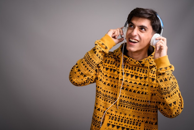 Young happy Persian teenage boy smiling and listening music with headphones