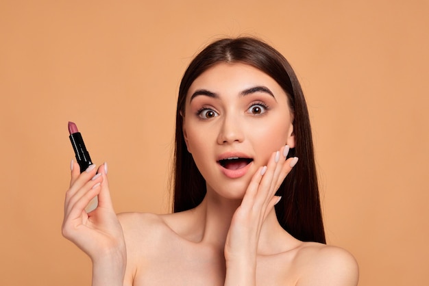 Young happy positive woman holding pink lipstick