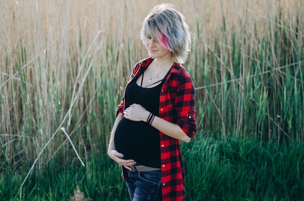 Young happy pregnant woman relaxing and enjoying life in nature. Outdoor shot.