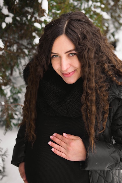 Young happy pregnant woman in snowy park