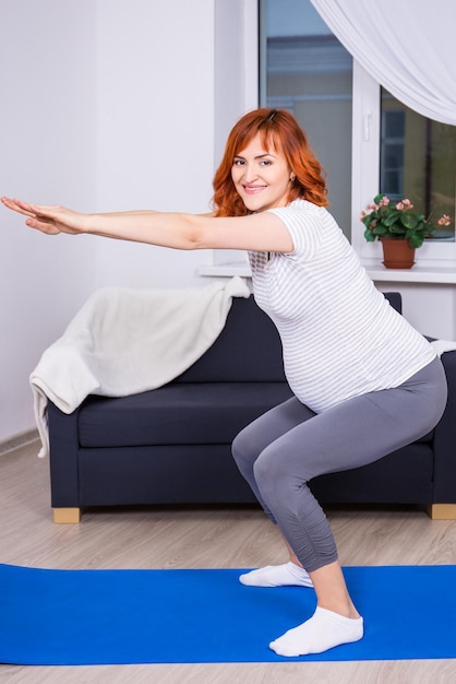 Young happy pregnant woman squatting at home