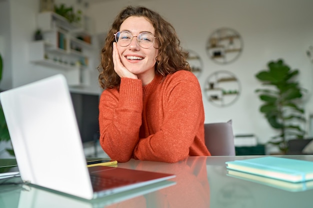 Foto giovane studente donna graziosa felice seduto in ufficio a casa con il computer portatile ritratto