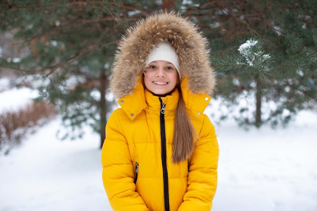 Young happy smiling child in yellow coat in winter park