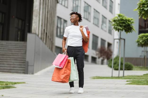 Photo young happy smiling fashionable african american woman holding paper shopping bags