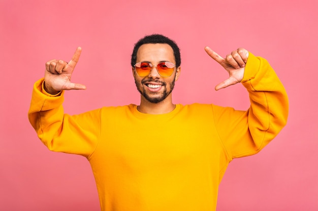 Un giovane uomo divertente sorridente felice isolato sopra il colore rosa.