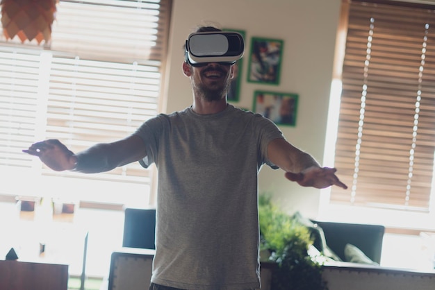 a young happy smiling man using virtual reality vr glasses indoors