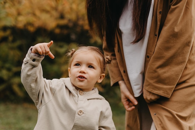 腕の中で彼女の小さな娘と一緒に若い幸せで笑顔のお母さんは、週末を秋の公園での散歩に費やし、セレクティブ フォーカス ノイズ効果秋の気分を抱いてキスします