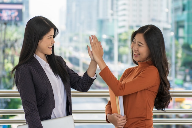 Photo young happy student holding books and slap hands or hi five together at campus.