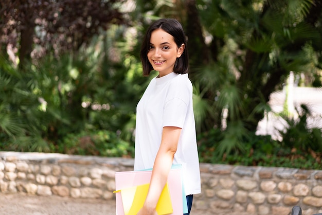 Young happy student woman holding notebooks at outdoors