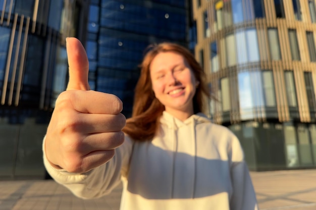 Фото Молодая счастливая успешная женщина, студентка колледжа или университета, показывает большой палец вверх, как жест и улыбается