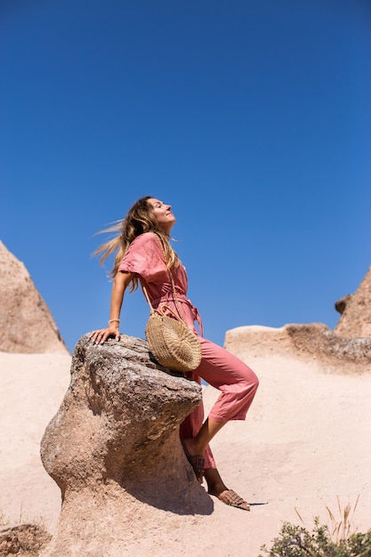 Young happy tourist woman traveler in a pink dress enjoying a vacation in desert Cappadocia Turkey