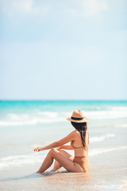 Молодая счастливая женщина на пляже наслаждается летним отдыхом женщина отдыхает на берегу моря