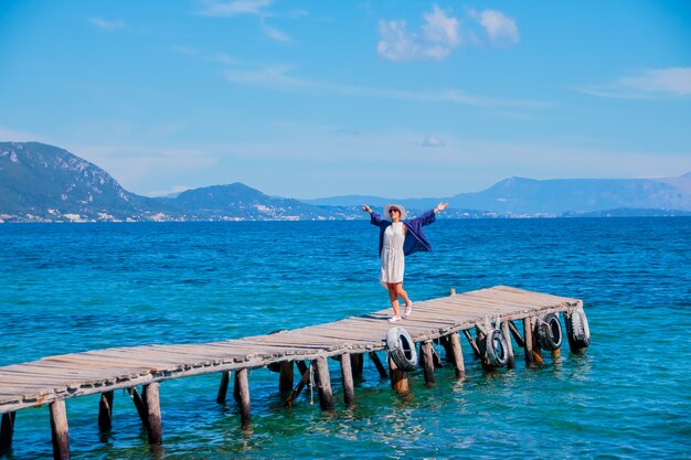 Giovane donna felice sul ponte vicino al mare, ora legale, concetto felice di vacanza.