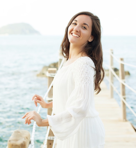 夏の時間、海の近くの橋の上の若い幸せな女