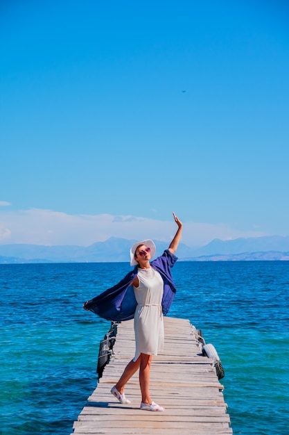 海の近くの橋の上の若い幸せな女