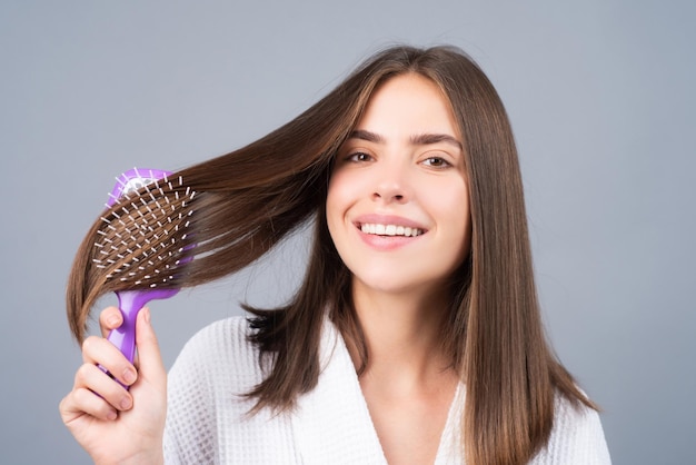 Young happy woman combing hair portrait of smiling female model with a comb brushing hair girl with