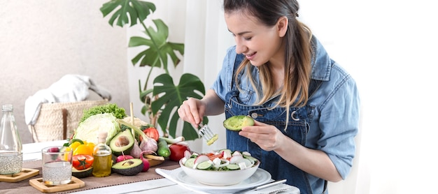 Young and happy woman eating salad at the table