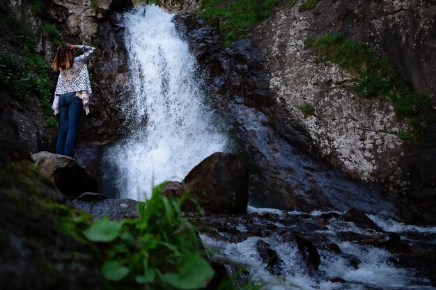 Young happy woman enjoing the summer waterfall