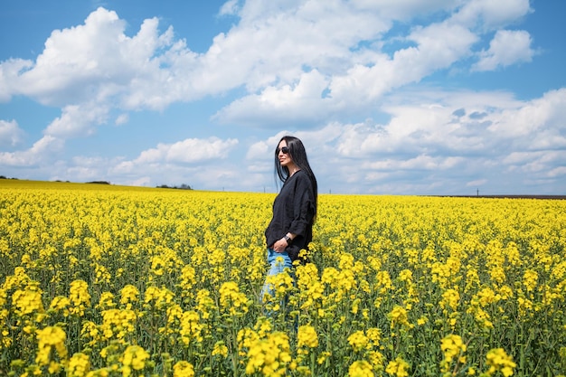 Giovane donna felice che gode del campo di canola.