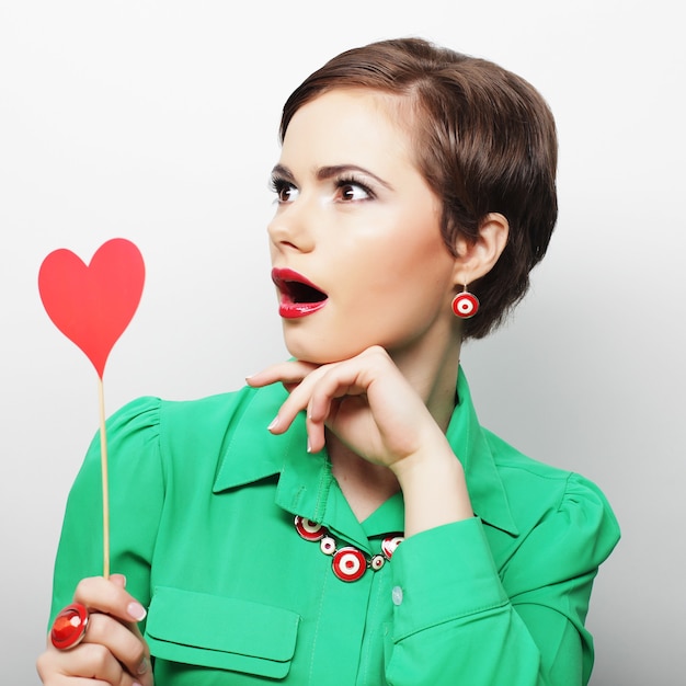 Young happy woman holding red  paper heart and ready for party