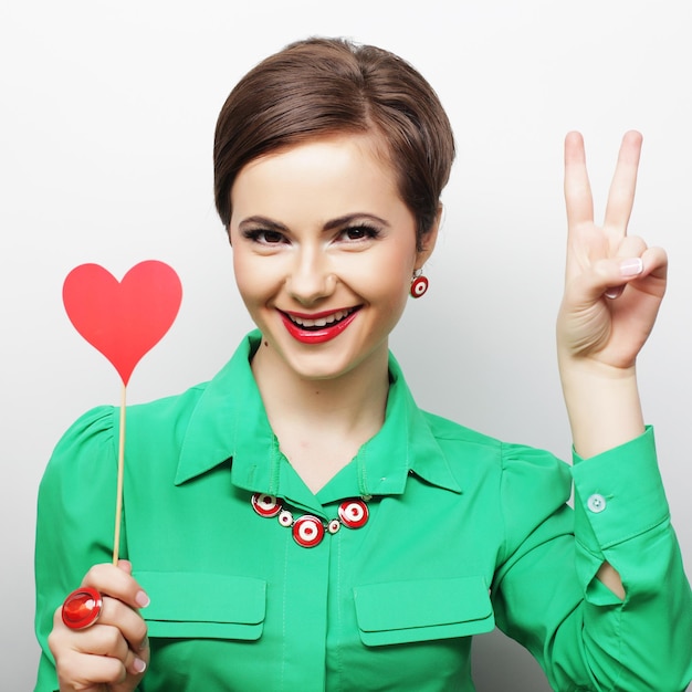 Young happy woman holding red paper heart and ready for party