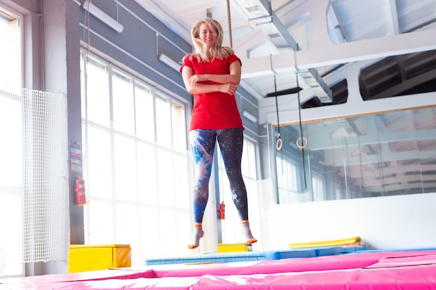 Young happy woman jumping on a trampoline indoors.