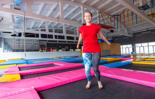 Young happy woman jumping on a trampoline indoors.