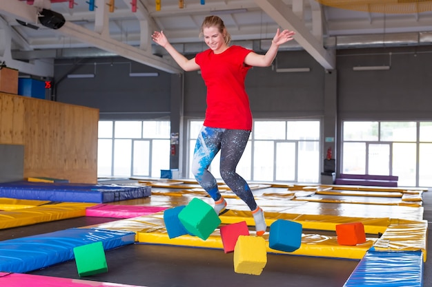 Young happy woman jumping on a trampoline indoors.