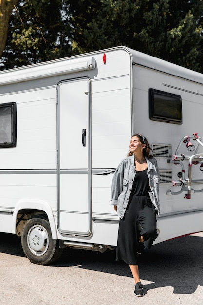 Foto giovane donna felice che si appoggia sul caravan