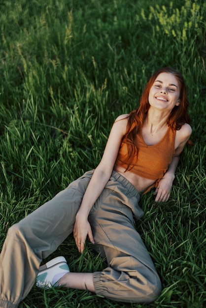 A young happy woman lying relaxed on the grass in the park the lifestyle of a happy person without depression