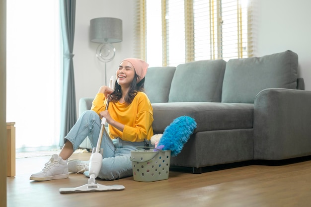 Giovane donna felice che pulisce e aspira il pavimento in soggiorno