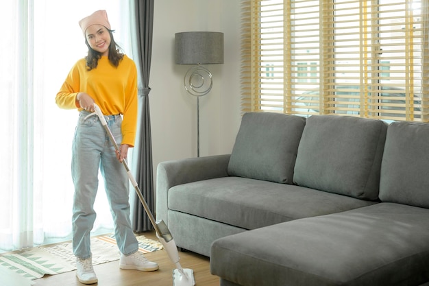 Young happy woman mopping and vacuum the floor in living room