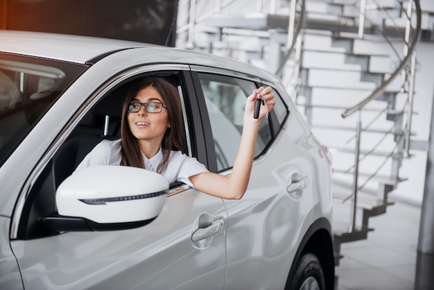 手にキーが付いている車の近くの若い幸せな女