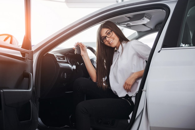 手にキーが付いている車の近くの若い幸せな女