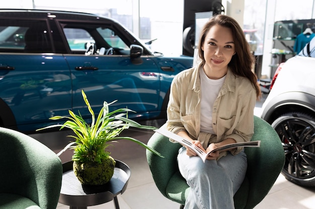 Young happy woman in new car dealership showroom