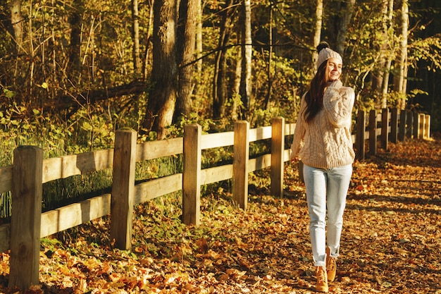 Young and happy woman in the park at sunny autumn day