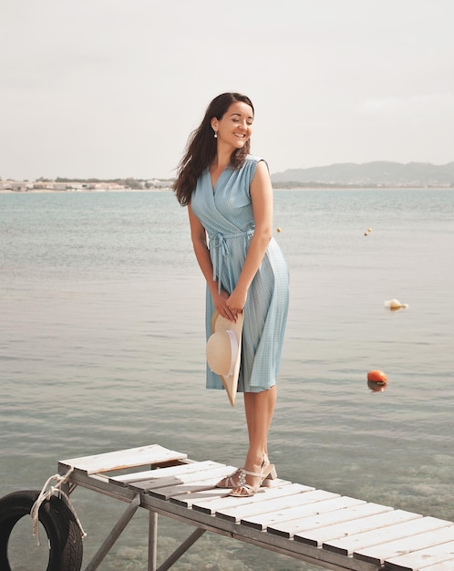 海の夏休みの近くでポーズをとって若い幸せな女性