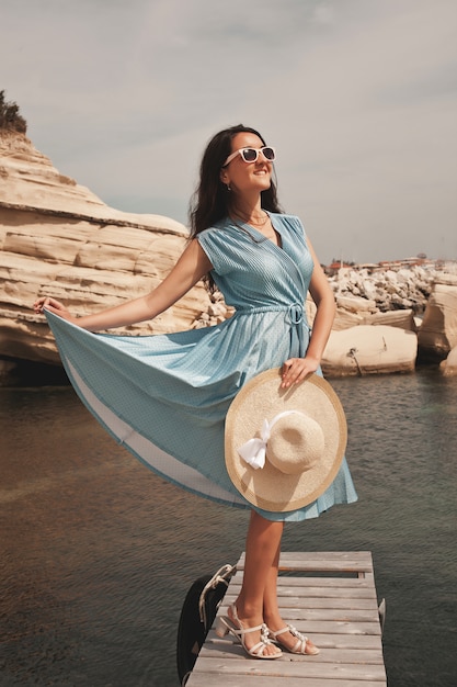 Giovane donna felice che posa vicino al mare