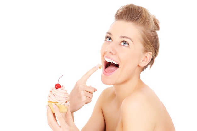 Foto una giovane donna felice in posa con un cupcake su sfondo bianco