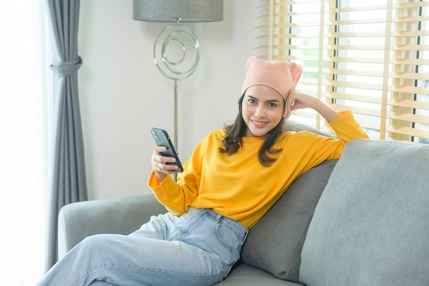 거실에서 스마트폰을 사용하여 휴식을 취하고 있는 젊은 행복한 여성