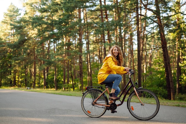 Young happy woman rides bicycle in sunny park Beautiful woman enjoys autumn nature Lifestyle