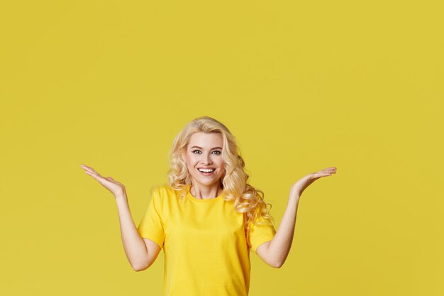 Young happy woman shows hands up, spreads his hands to the sides.