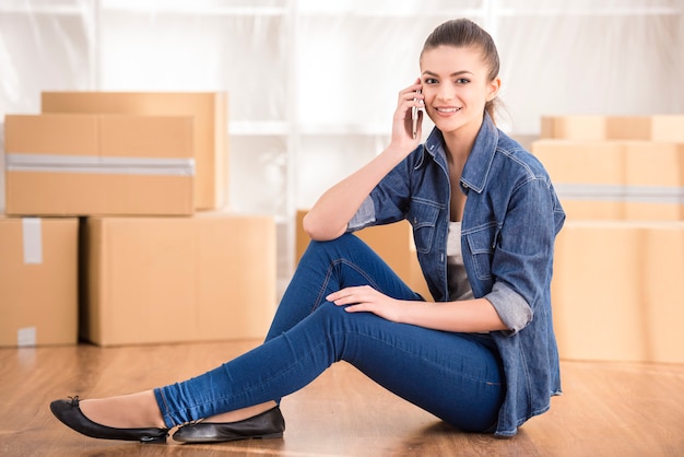 Young happy woman siting in a room near boxes.