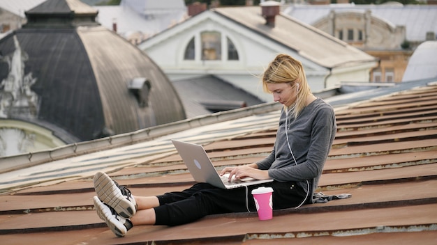 Young happy woman sits with coffee on the rooftop