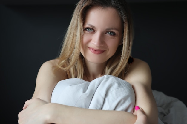 Photo young happy woman sitting in bed and smiling