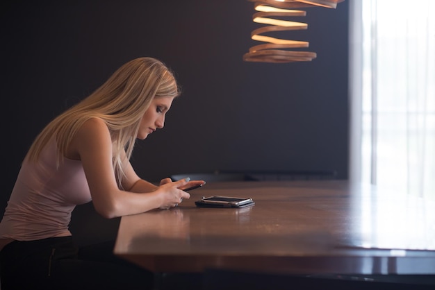 young happy woman sitting at the table and using mobile phone at luxury home