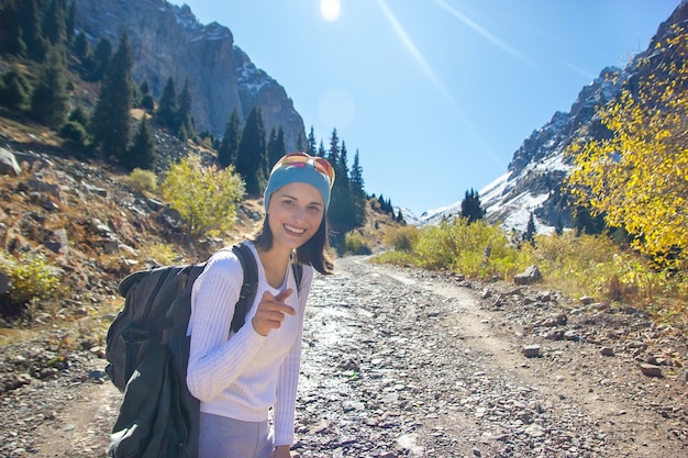 Foto una giovane donna felice sorride alla telecamera. sullo sfondo le montagne.