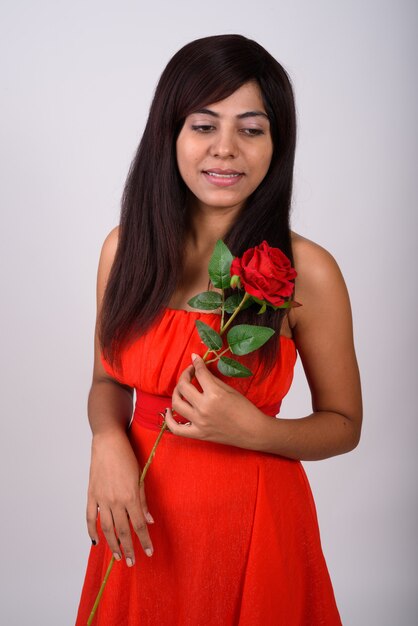 Young happy woman smiling and thinking while holding red rose ready for Valentine's day