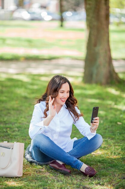 Young happy woman speaks by video call in nature