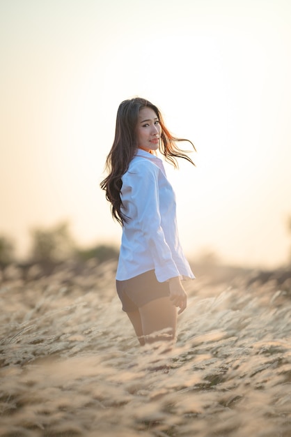 Молодая счастливая женщина, стоящая в поле в свете заката